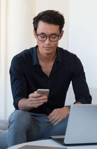 Мъж носи стъкла Есилор с дизайн Eyezen, докато използва смартфон.